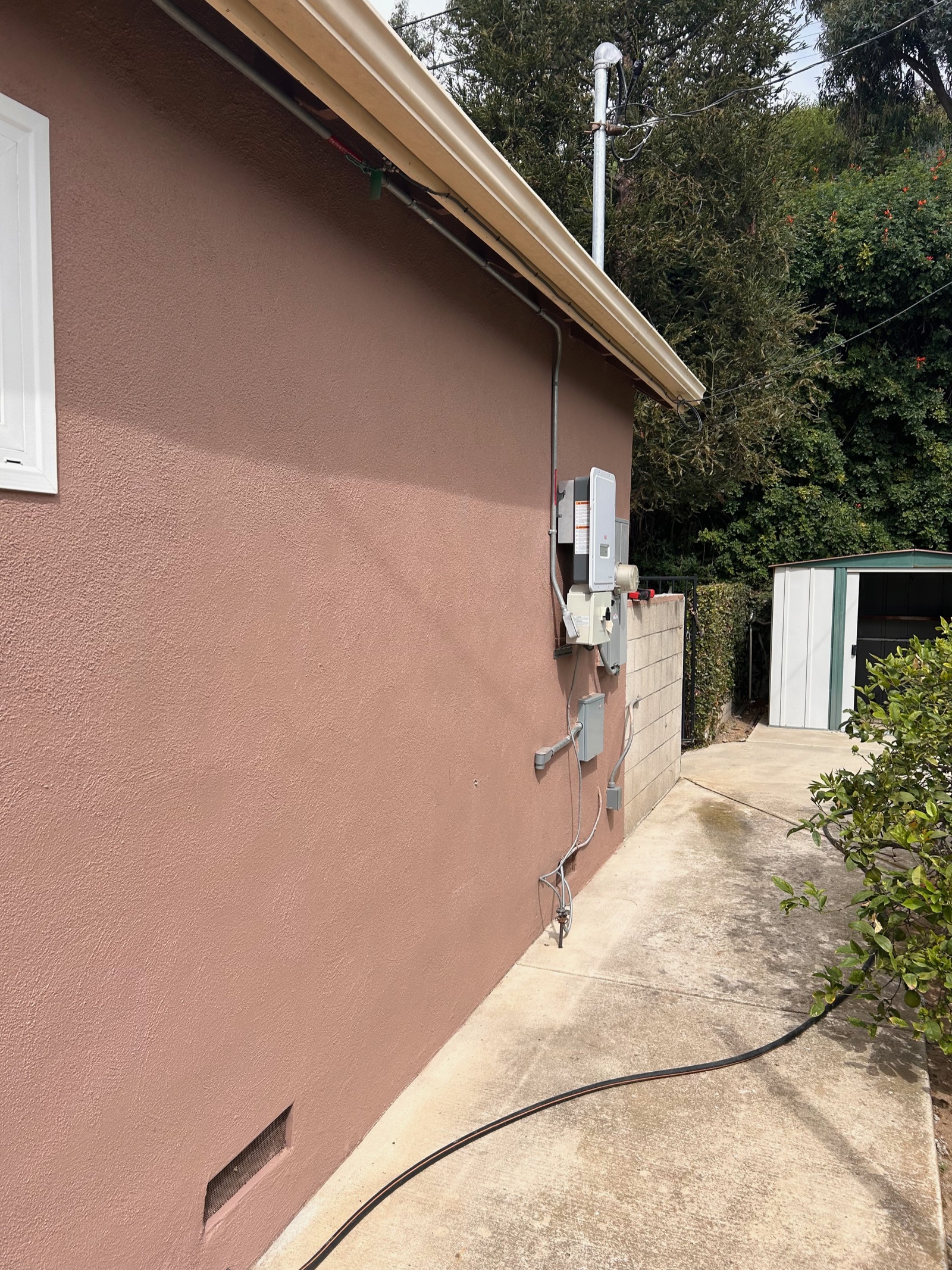 Exterior wall-mounted charging equipment with a tidy conduit run along a residential home